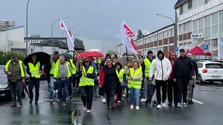 Mehrere Menschen in Warnwesten laufen in Bremerhaven über eine Straße.