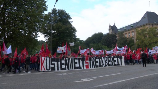 Viele Streikende einer Gewerkschaft laufen eine Straße entlang, auf einem Transparent steht "Küstenweit Streikbereit".