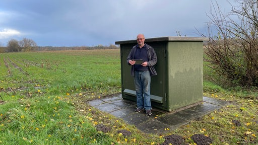 Ein Mann mit Tablet in der Hand steht vor einem Stromkasten.