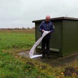 Ein Mann steht mit einem Langen Blatt Papier vor einem Stromkasten