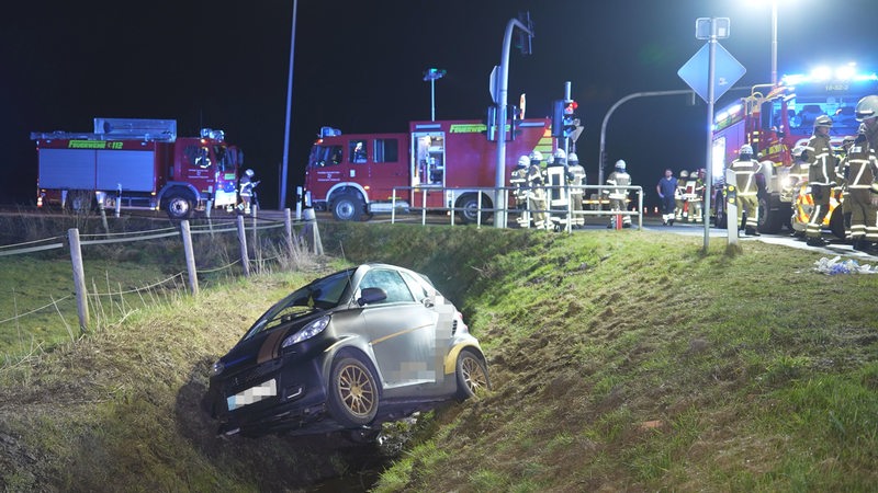 Ein Auto, das von der Straße abgekommen ist, liegt abseits einer Kreuzung in einem Graben.