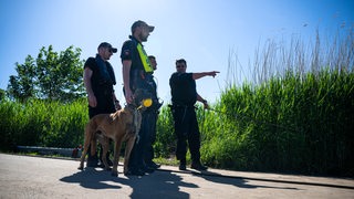 Einsatzkräfte der Polizei stehen bei der Suche nach dem vermissten Arian mit einem Spürhund an der Oste.