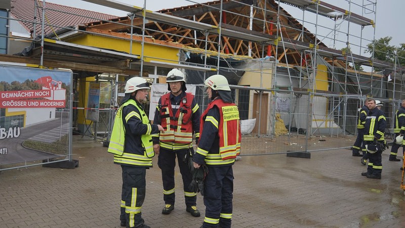 Feuerwehrleute stehen vor einer eingestürzten Decke eines Supermarktes