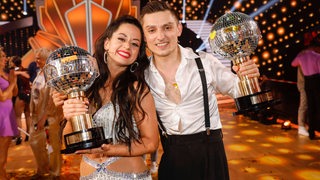 Das Bremer Tanzpaar Malika Dzumaev und Zsolt Sandor Cseke halten bei der Sendung "Let's Dance" strahlend ihre Siegerpokale der Profi-Challenge hoch.