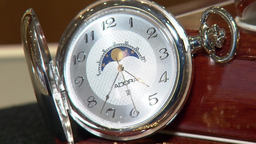 Eine silberne Taschenuhr mit Mond und Sternen in der Mitte des Ziffernblattes