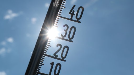 Vor einem blauen bewölkten Himmel zeigt ein Außenthermometer eine Temperatur von knapp 40 Grad an.