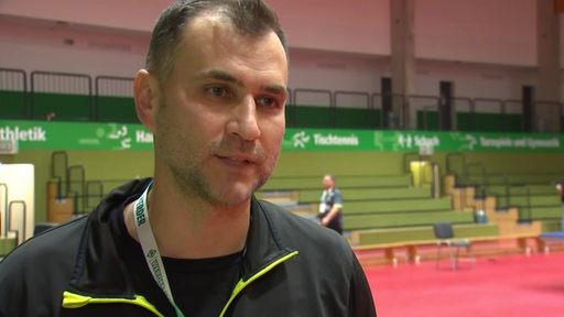 Werders Tischtennis-Coach Cristian Tamas steht in der fast leeren Halle nach dem Spiel beim Interview.