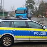 Ein Lkw und ein Polizeiauto stehen auf einem Parkplatz.