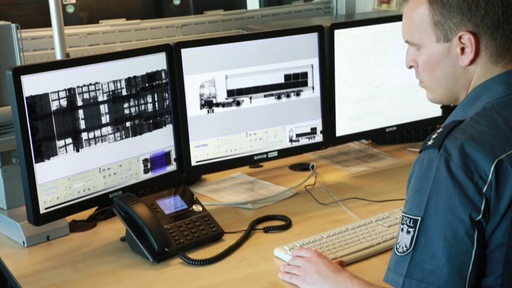 Ein Zollbeamter durchsucht auf einem Computerbildschirm zu erkennenden Lastwagen.
