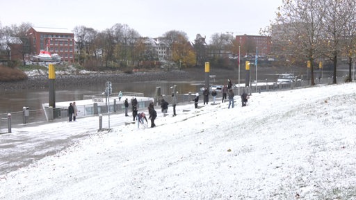 Mehrere Menschen spielen im Schnee an der Weser.