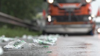 Plastikflaschenreste liegen vor einem Lkw auf der Fahrbahn.