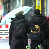 Eine Frau mit einem Regenschirm geht eine Straße entlang