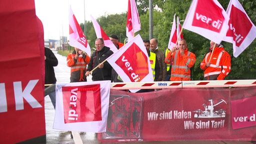 Mitglieder der Ver.di streiken in roter Montur und mit Fahnen in den Bremer Häfen.