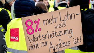  Beschäftigte stehen mit Schildern am Treffpunkt für einen Demonstrationszug vor dem Klinikum Oldenburg.