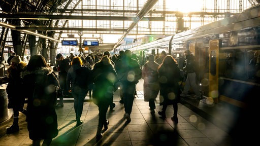 Reisende stehen an einem Gleis vom Bremer Hauptbahnhof. 