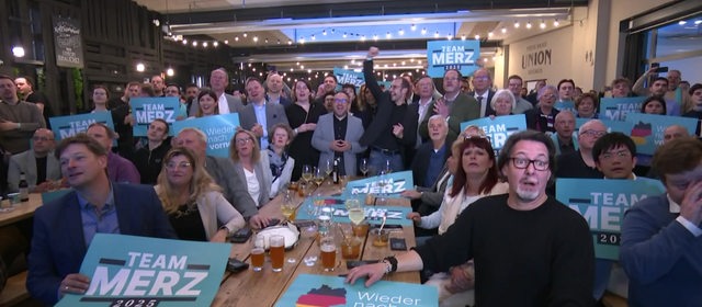 Die CDU in Bremen feiert die Wahlergebnisse mit Schildern und Merz-Plakaten.