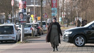 Eine Frau mit Kopftuch vor verschiedenen Wahlplakaten