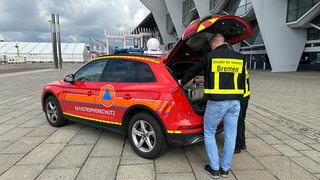 Ein rotes Auto mit der Aufschrift "Katastrophenschutz" steht auf der Bürgerweide. Ein Mann mit Warnjacke der Innenbehörde steht am Kofferraum und schaut hinein.