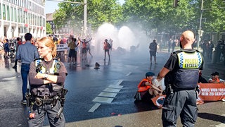 Ein Wasserwerfer spritzt auf Demonstranten