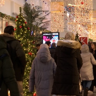 Menschen gehen durch eine weihnachtlich geschmückte Mall