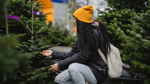 Eine Frau beim Kauf eines Weihnachtsbaumes