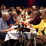 Menschen sitzen an einer langen Tafel und essen