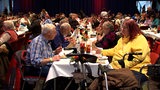 Menschen sitzen an einer langen Tafel und essen