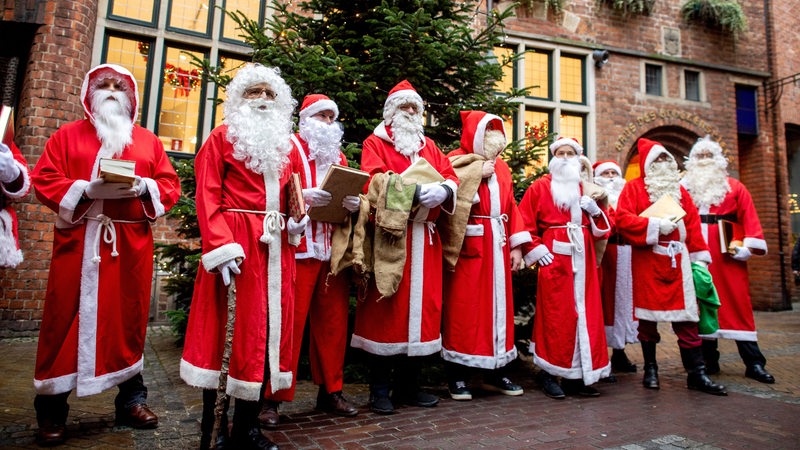 Zahlreiche Weihnachtsmänner aus Bremen singen während einer Versammlung gemeinsam in der Böttcherstraße.