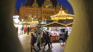 Blick durch die Arkaden auf den Bremer Weihnachtsmarkt mit dem Rathaus im Hintergund.