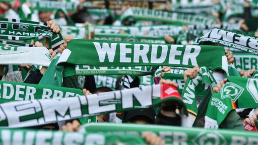 Werderfans halten ihre Schals in die Höhe.