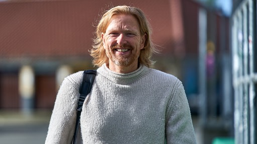 Björn Schierenbeck läuft über Werders Vereinsgelände und grinst dabei.