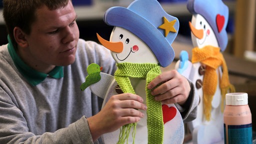 Schneemannfiguren werden von einem Mitarbeiter der Lebenshilfe in Magdeburg gefertigt.