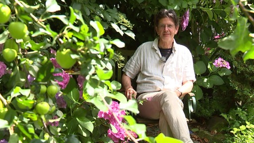 Zu sehen ist der Künstler Werner Henkel in seinem Garten.