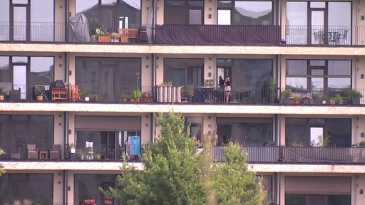 Mehrere Ebenen von Balkonen in einem Wohnhaus, auf einem davon steht eine Frau.