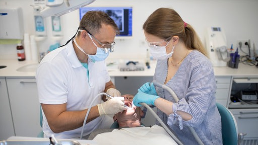 Zahnarzt und zahnmedizinische Fachangestellte bei einer Behandlung eines Patienten (Symbolbild)