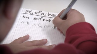 Ein Kind schreibt auf einem Papier mehrere Regeln auf