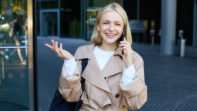 Eine junge Frau telefoniert und lacht dabei.