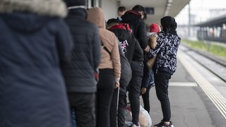 Flüchtlinge aus einem Zug aus Österreich werden von Grenzwächtern zur Kontrolle gebracht.